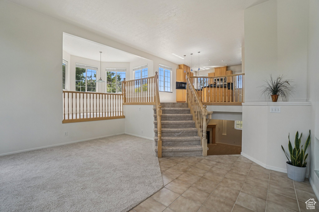 Unfurnished living room featuring healthy amount of natural light, stairs, and light tile patterned floors