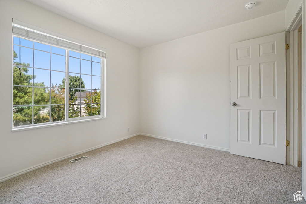 Carpeted spare room featuring baseboards and a smoke detector