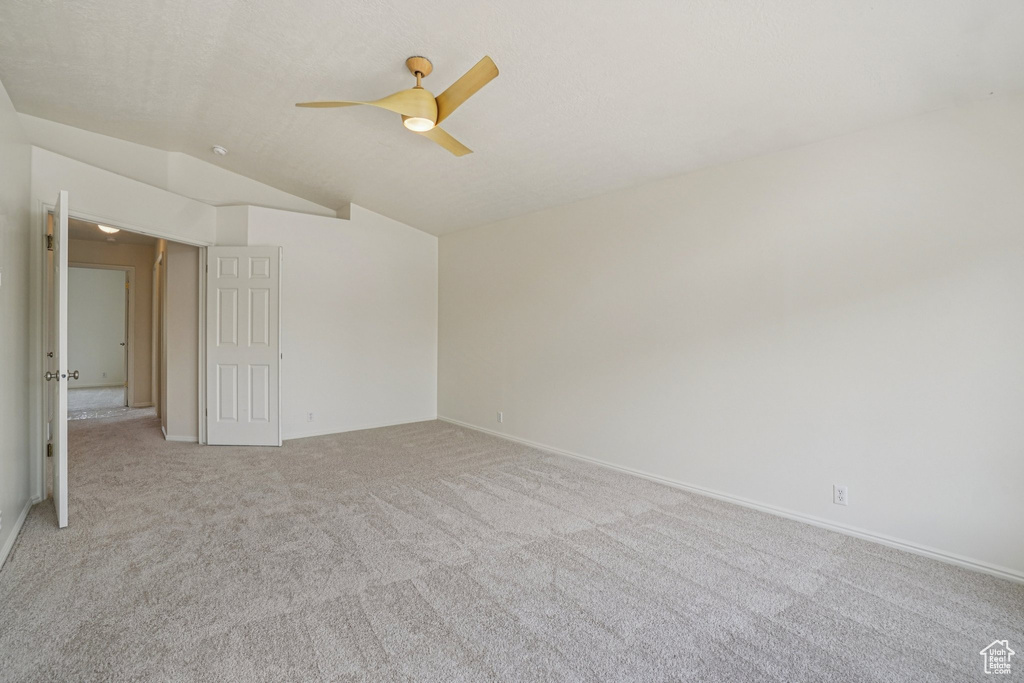 Unfurnished room with vaulted ceiling, a ceiling fan, and light colored carpet