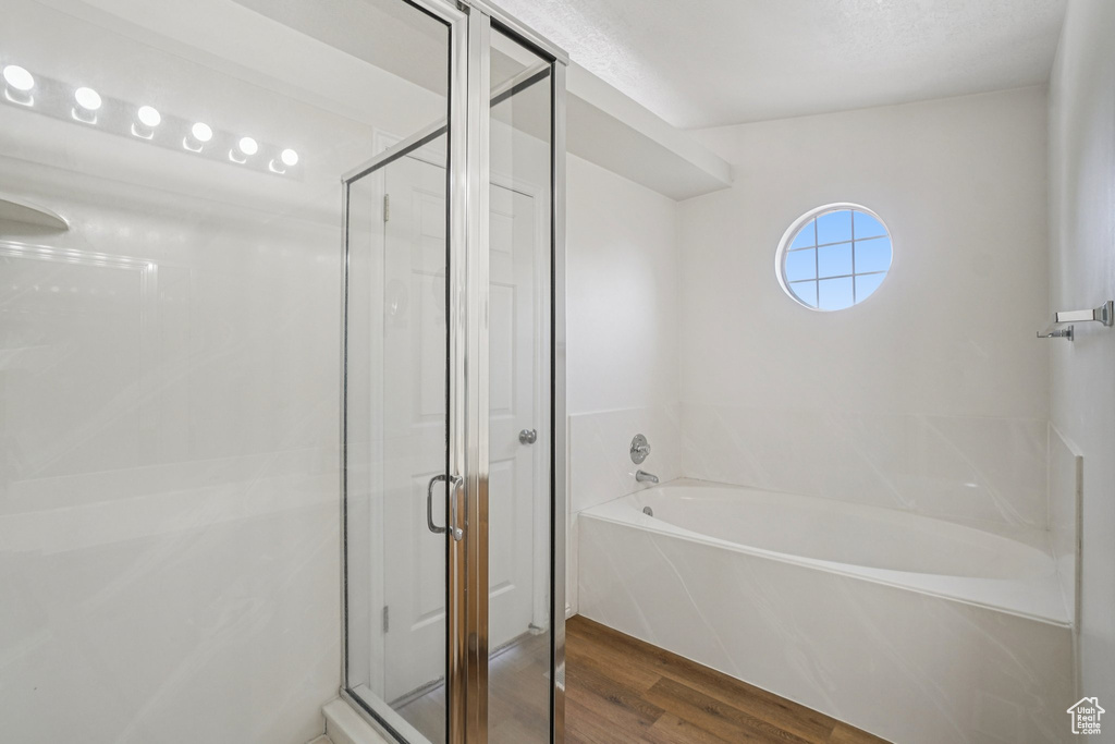 Full bath with wood finished floors, a bath, and a shower stall
