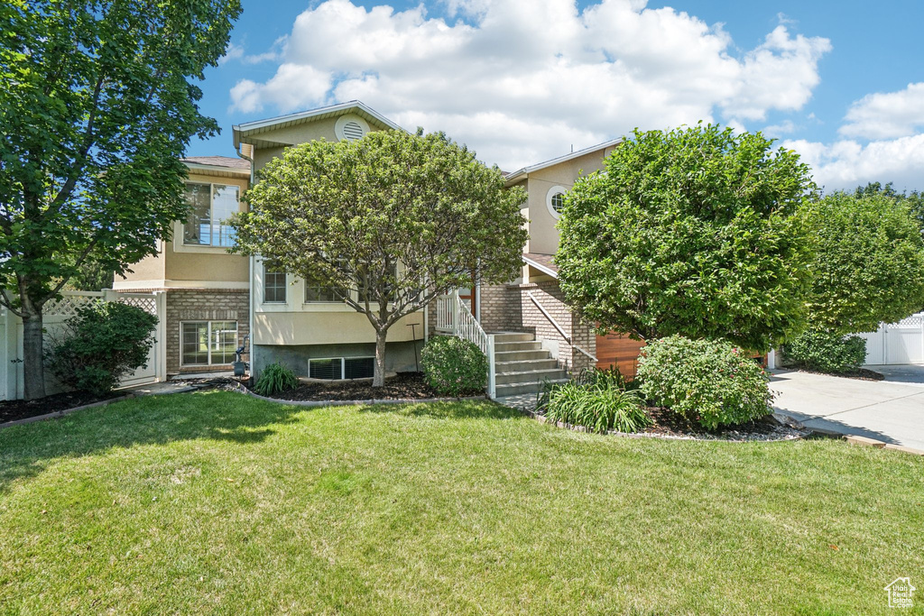 Obstructed view of property with stucco siding and a front lawn