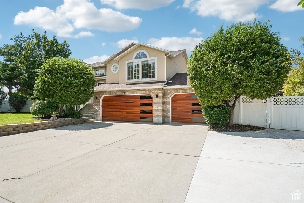 View of front facade featuring an attached garage, driveway, stucco siding, and brick siding
