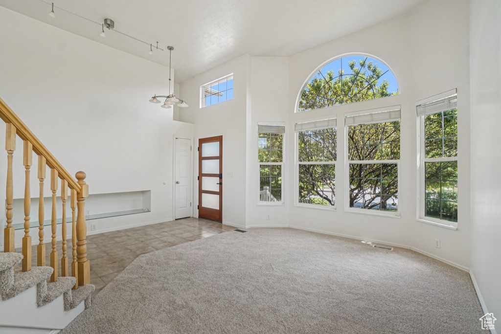 Carpeted foyer featuring a high ceiling, stairs, and tile patterned floors