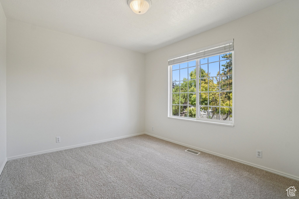 Carpeted spare room featuring baseboards