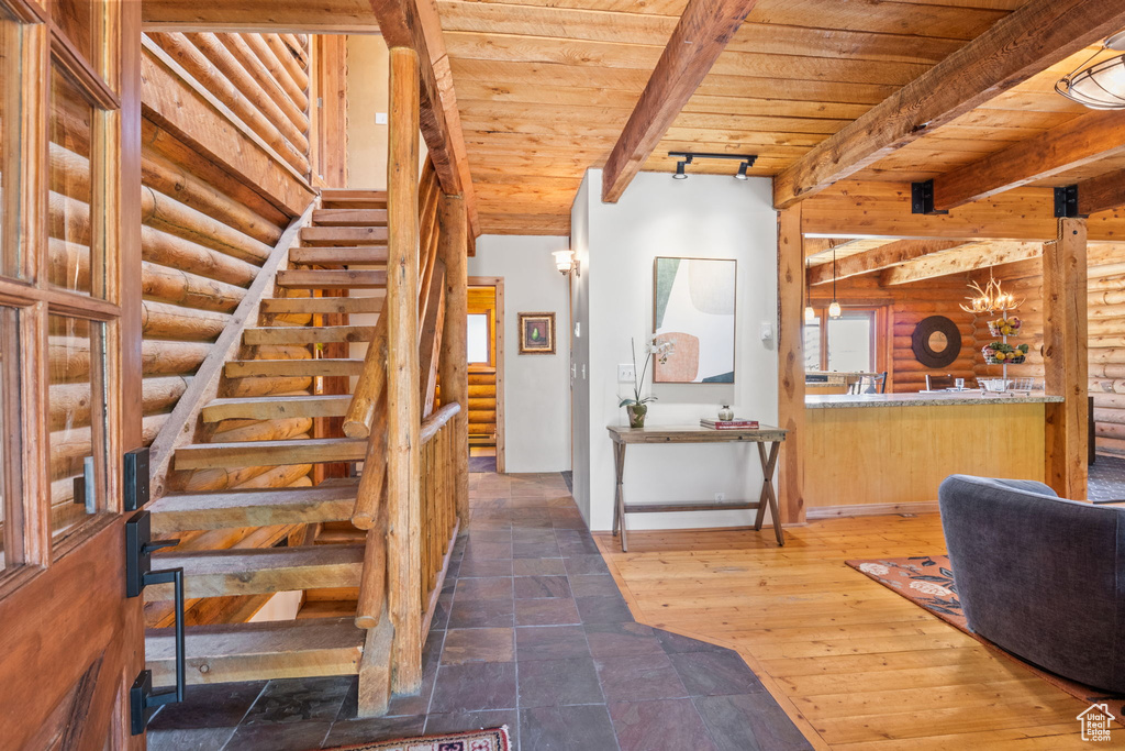 Staircase featuring a wooden ceiling with exposed beams and rustic walls