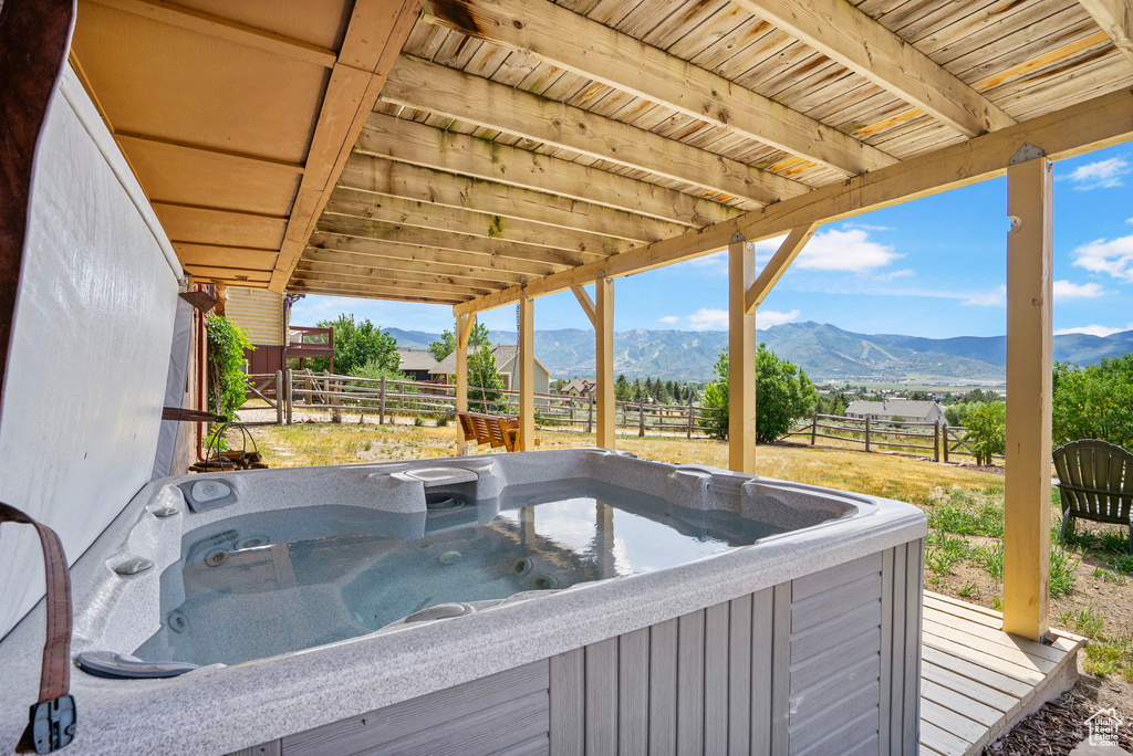 Wooden terrace featuring a hot tub, a mountain view, and a fenced backyard