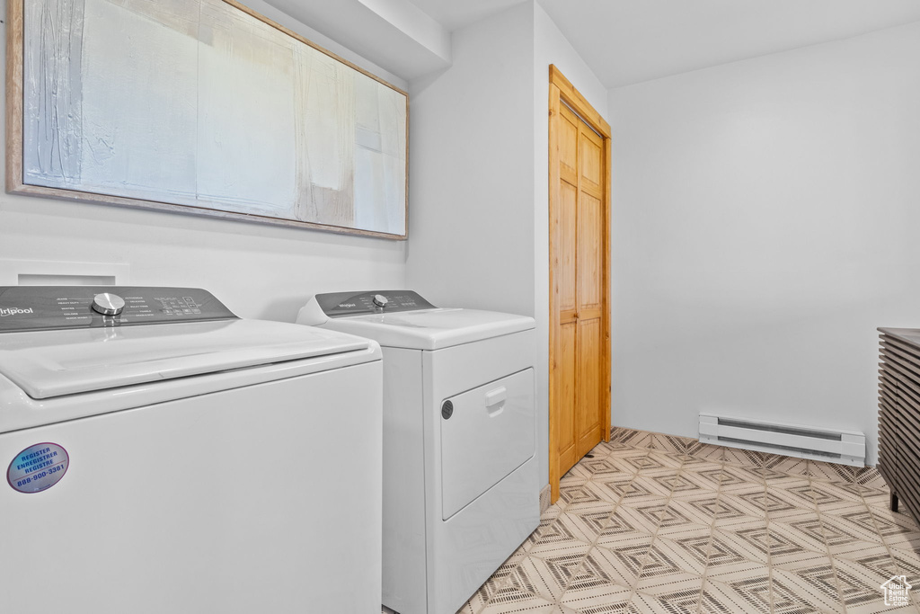 Laundry area with baseboard heating, washer and clothes dryer, and cabinet space