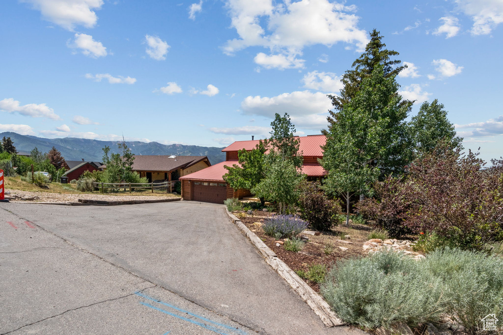 View of front facade featuring a garage, driveway, a mountain view, and a metal roof