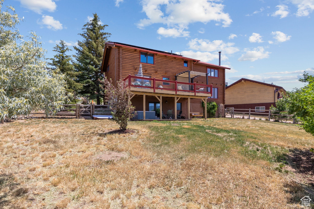 Back of house featuring a deck and faux log siding