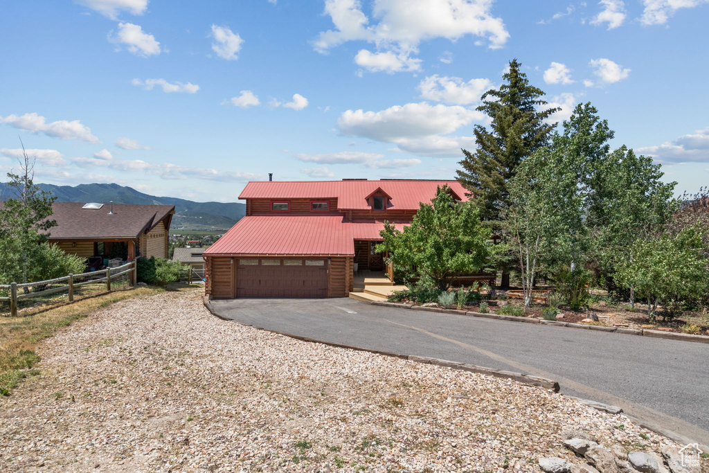 View of front of house featuring driveway, a mountain view, a garage, and a metal roof