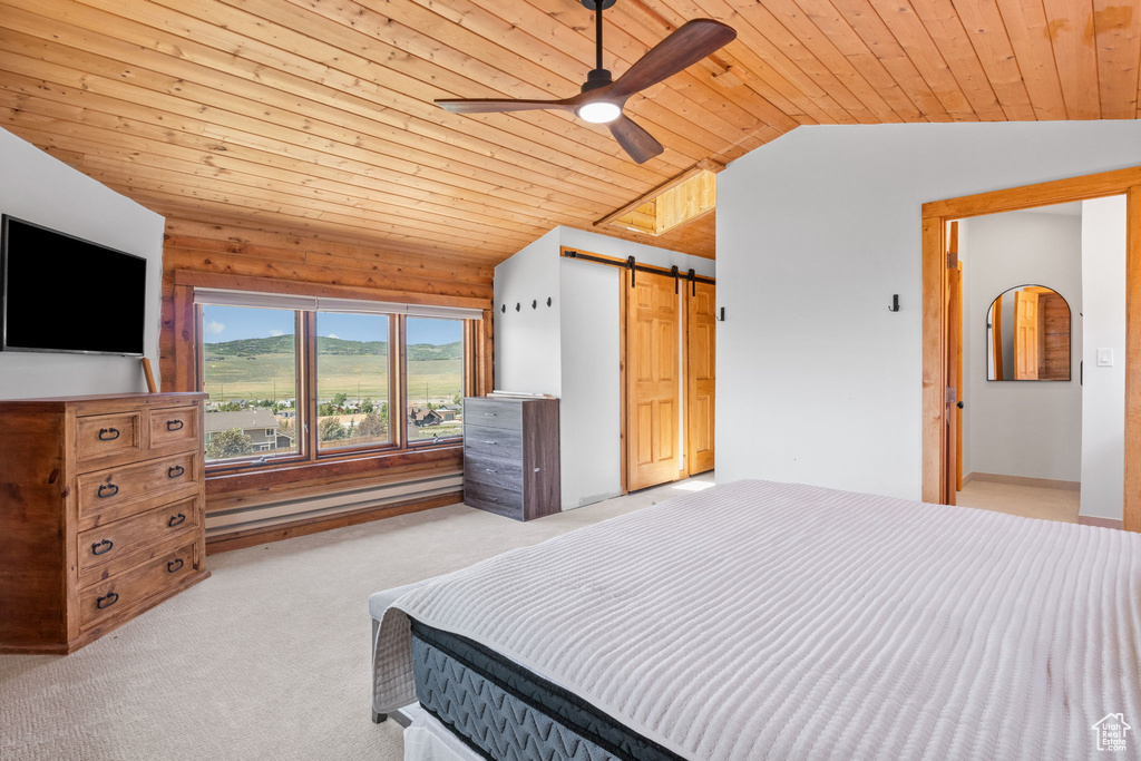 Bedroom with vaulted ceiling, wooden ceiling, carpet flooring, a barn door, and ceiling fan