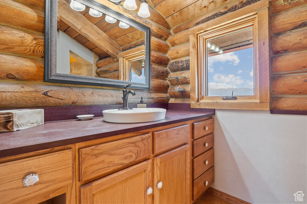 Bathroom featuring log walls, wooden ceiling, and vanity