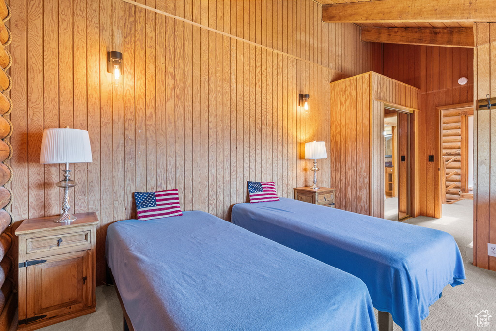 Bedroom featuring carpet, beam ceiling, and wood walls