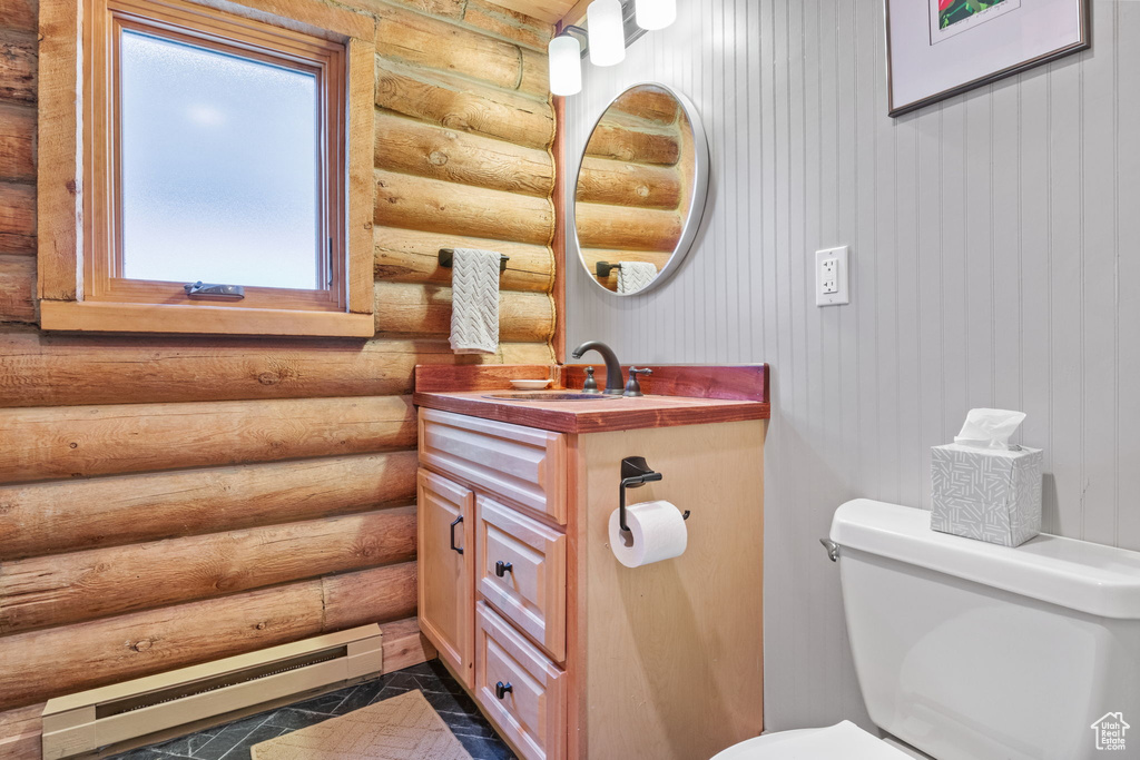Bathroom with a baseboard heating unit, log walls, and vanity