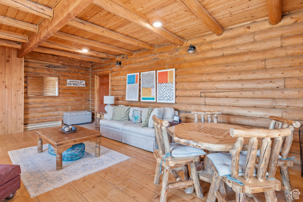 Living room with a wooden ceiling with exposed beams, hardwood / wood-style floors, and log walls
