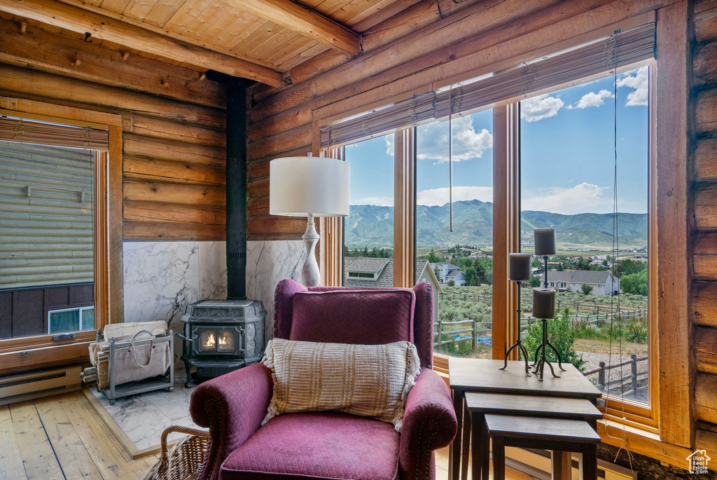 Sitting room featuring a wood stove, a mountain view, a wood ceiling with exposed beams, wood-type flooring, and baseboard heating