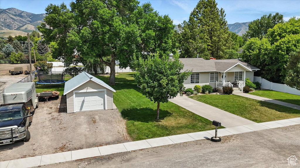 Single story home with a trampoline, an outbuilding, a mountain view, a porch, and dirt driveway