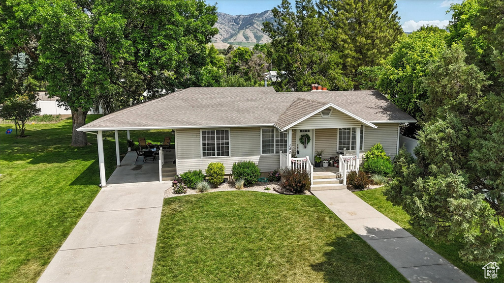 View of front of house with driveway, a shingled roof, an attached carport, a front lawn, and covered porch