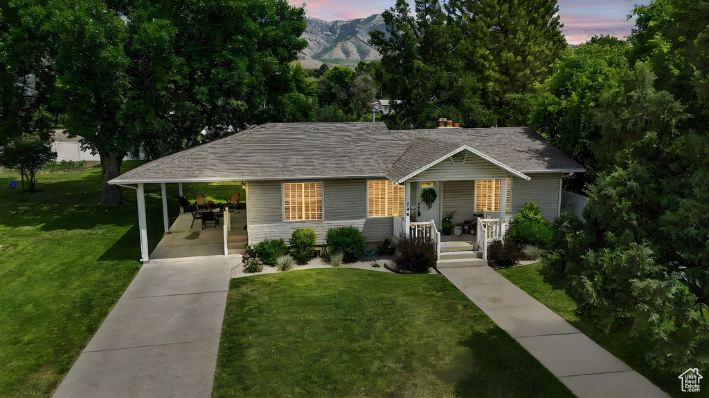 View of front of home featuring a porch, driveway, a front yard, a carport, and a mountain view