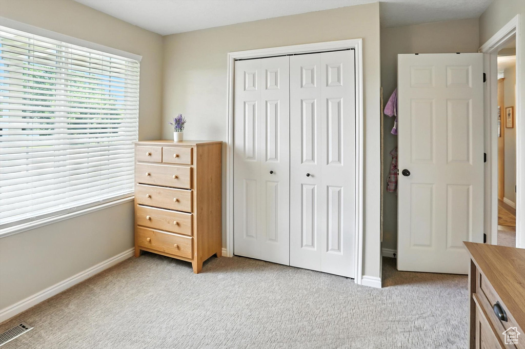 Bedroom with light carpet and a closet