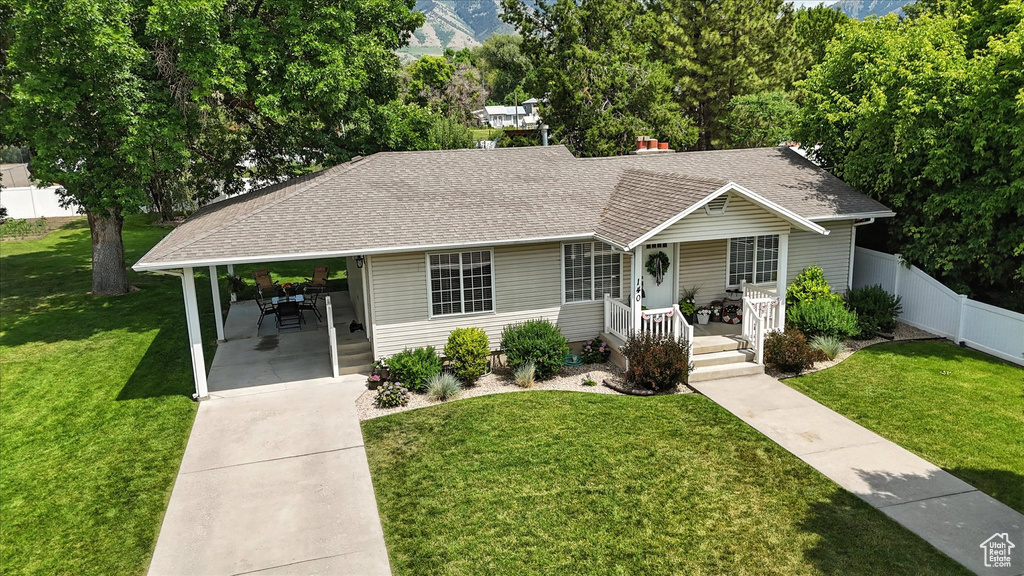 View of front facade featuring a porch, concrete driveway, a shingled roof, and an attached carport