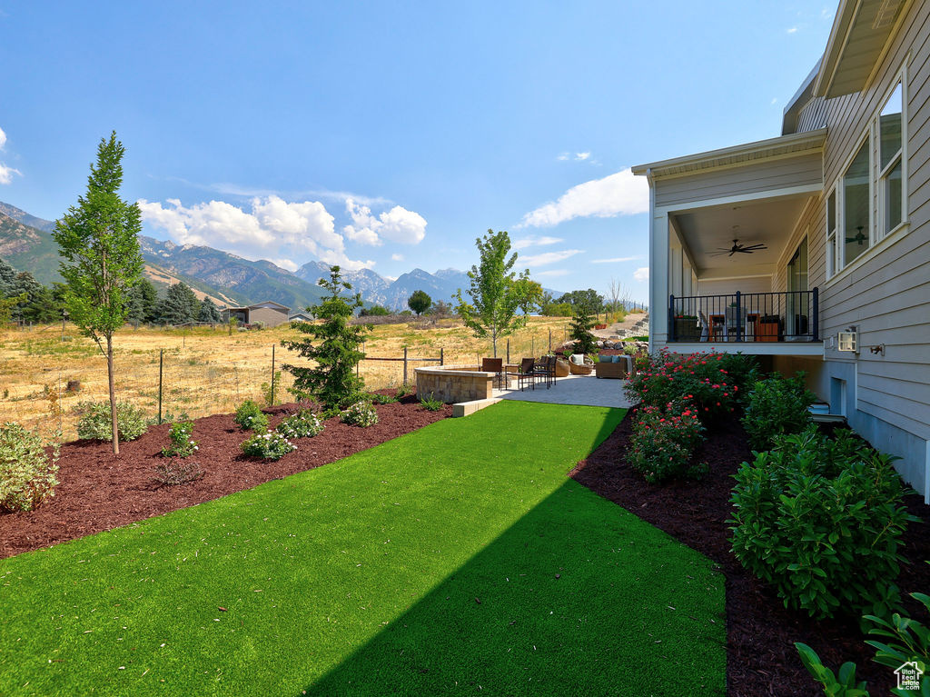 View of yard featuring ceiling fan, a mountain view, and a patio