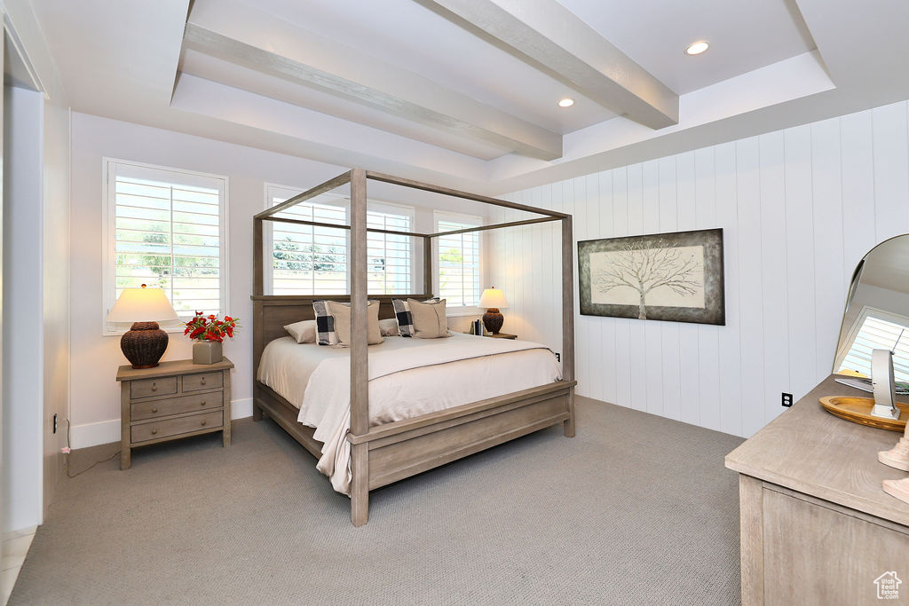 Bedroom featuring light colored carpet, multiple windows, and beamed ceiling