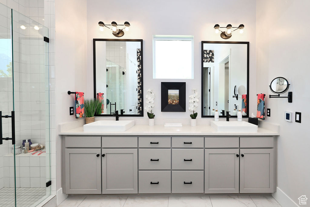 Bathroom with a stall shower, double vanity, and marble look tile flooring