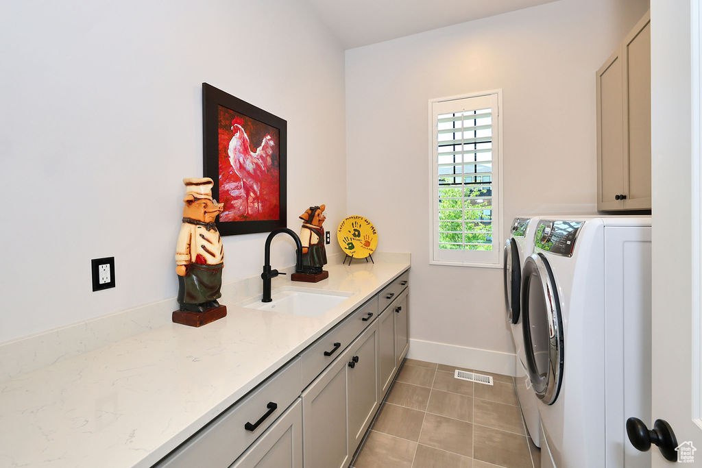 Washroom featuring independent washer and dryer, cabinet space, and light tile patterned floors