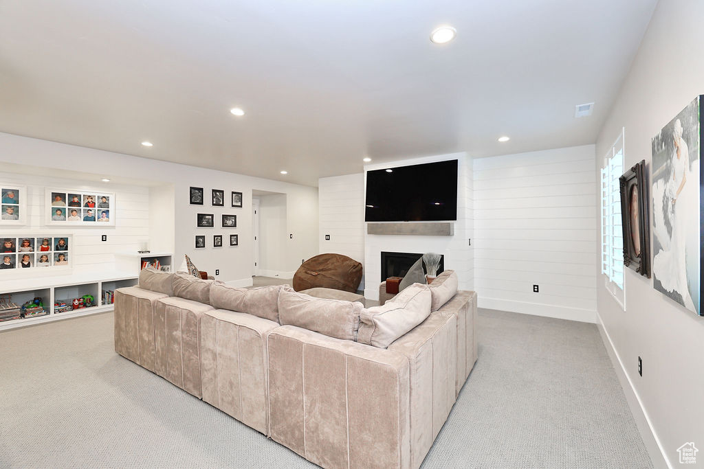Living room with light colored carpet, a large fireplace, and recessed lighting