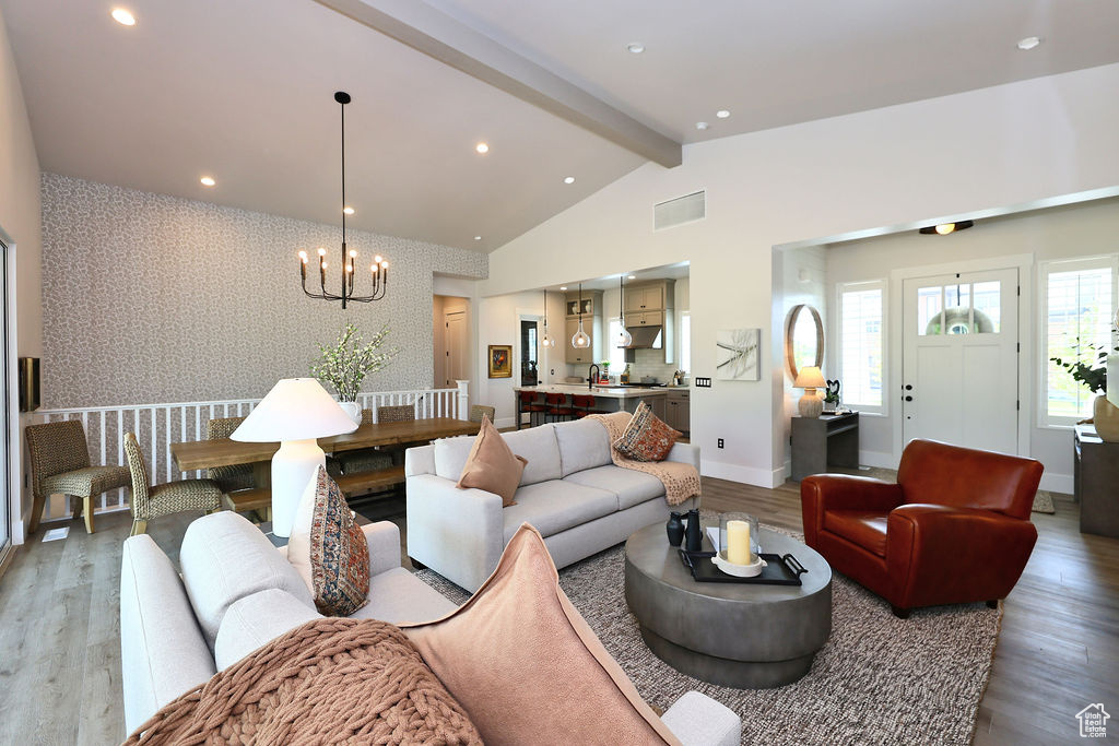 Living area featuring a chandelier, light wood-type flooring, an accent wall, wallpapered walls, and recessed lighting