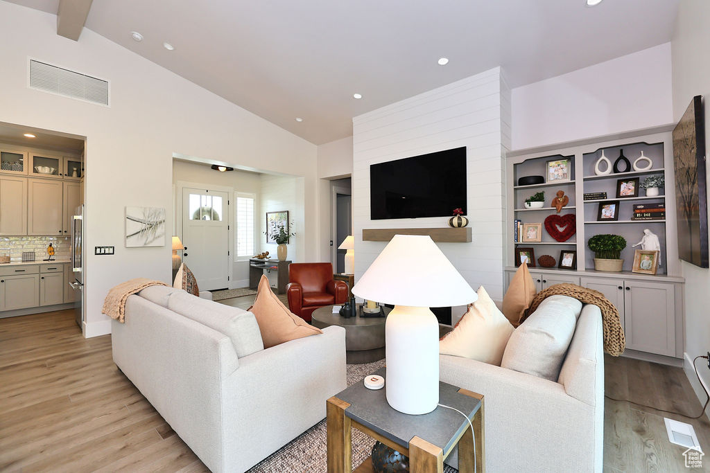 Living area with light wood-style floors, high vaulted ceiling, recessed lighting, and beam ceiling