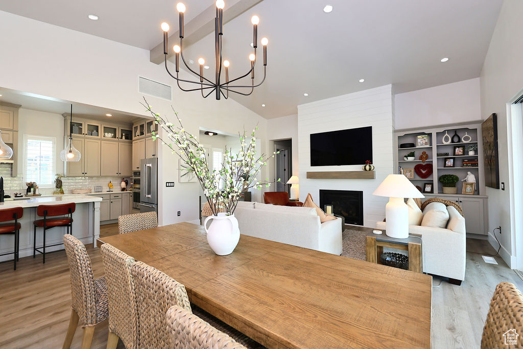 Dining area with light wood finished floors, a fireplace, recessed lighting, and a chandelier