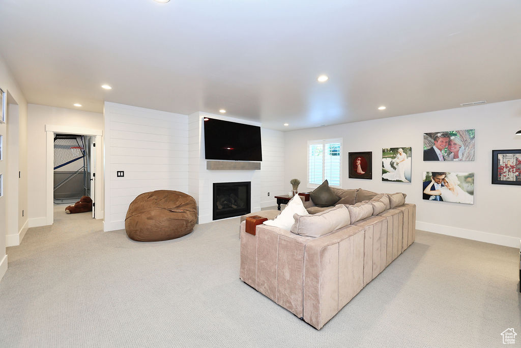 Living room with light colored carpet, recessed lighting, and a large fireplace
