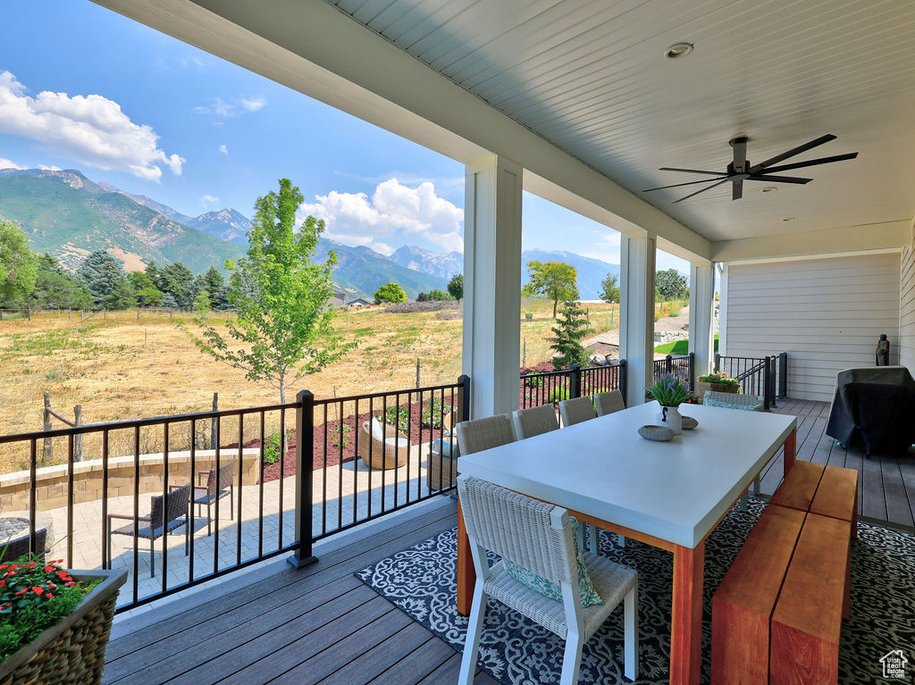 Deck featuring a mountain view, ceiling fan, outdoor dining area, and a grill