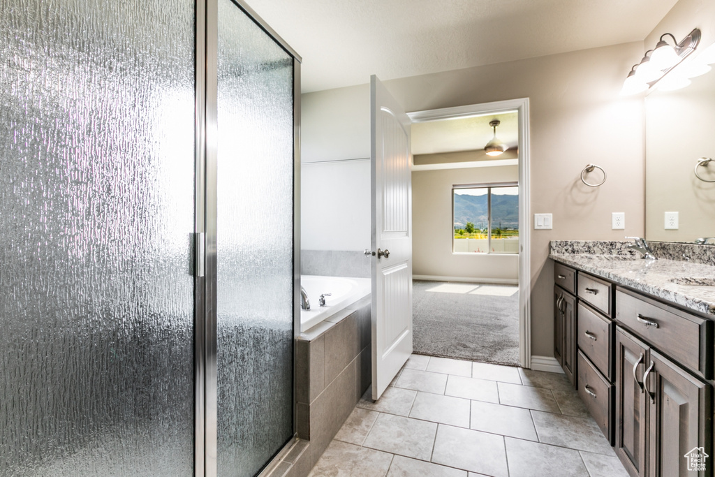 Full bath with double vanity, a bath, a shower stall, and tile patterned floors