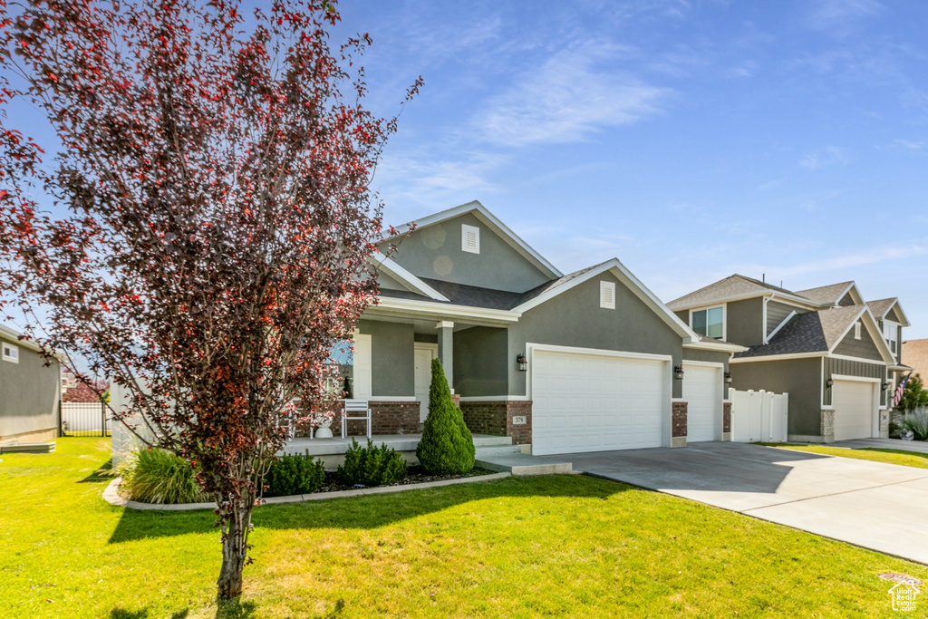 View of front of property with covered porch, a garage, concrete driveway, stucco siding, and roof with shingles