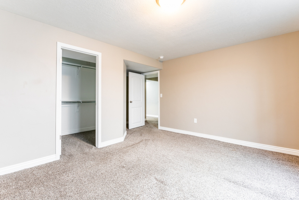 Unfurnished bedroom with carpet floors, a spacious closet, and a closet
