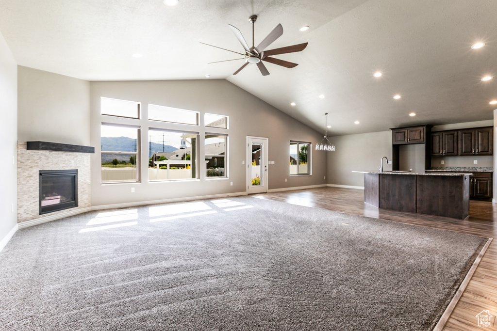 Unfurnished living room with ceiling fan, recessed lighting, a stone fireplace, light wood finished floors, and high vaulted ceiling