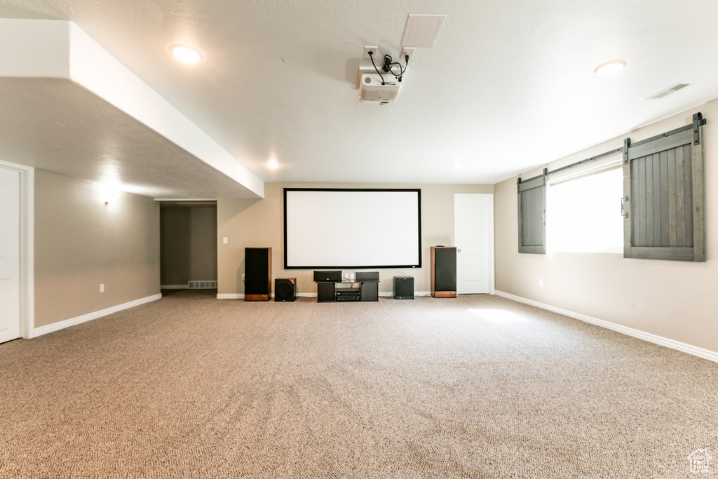 Carpeted cinema room featuring baseboards and a barn door
