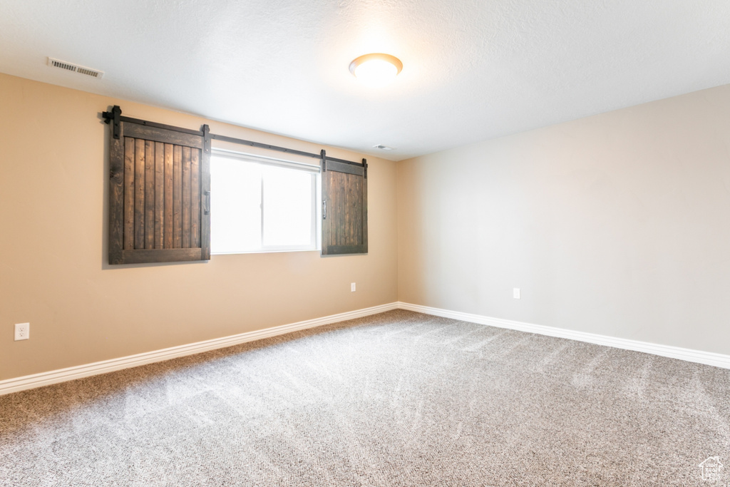 Carpeted empty room featuring a barn door