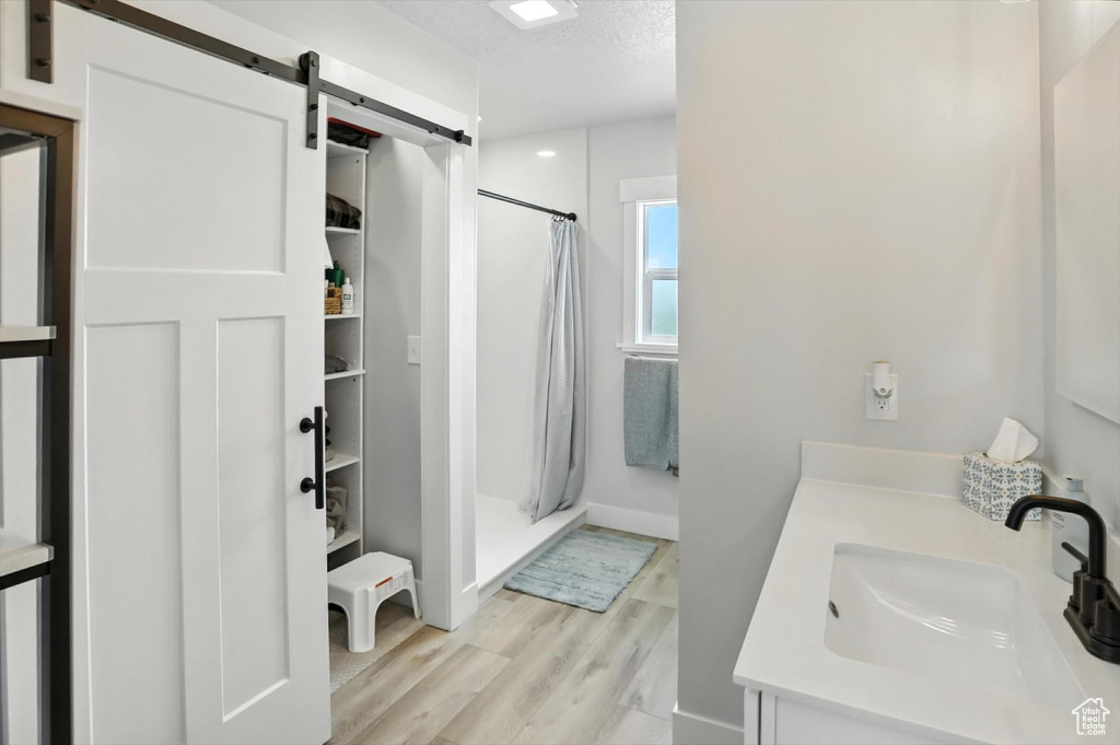 Bathroom with wood finished floors, a shower stall, vanity, and a textured ceiling