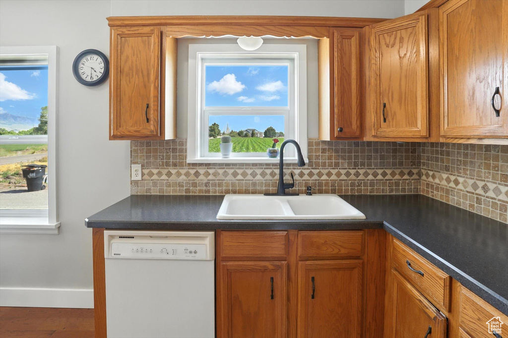 Kitchen featuring dishwasher, dark countertops, tasteful backsplash, and brown cabinetry