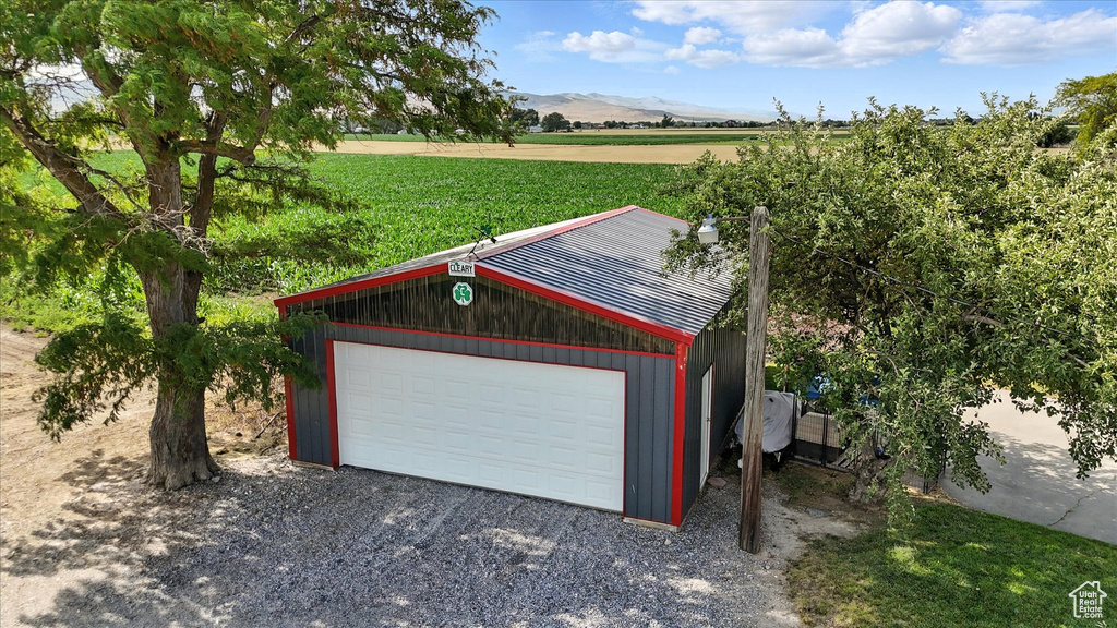 Detached garage featuring a view of countryside, a mountain view, and gravel driveway