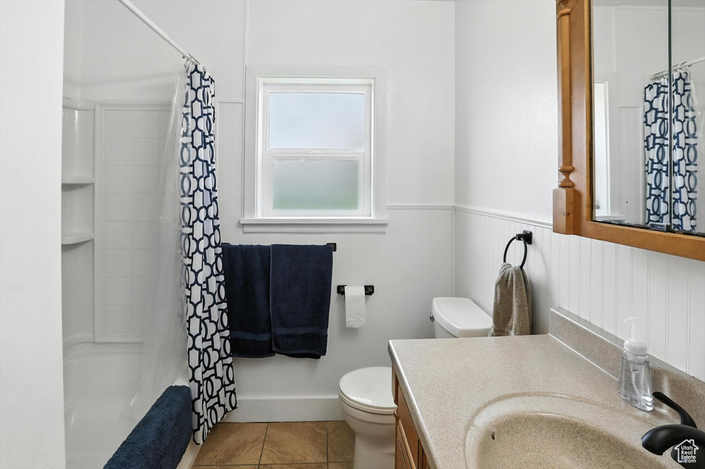 Bathroom with vanity, tile patterned flooring, a wainscoted wall, and shower / bath combo