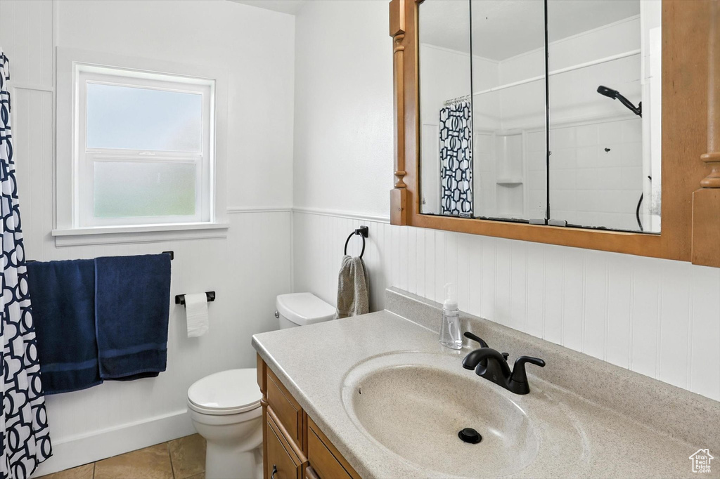 Full bathroom with vanity, curtained shower, a wainscoted wall, and tile patterned flooring
