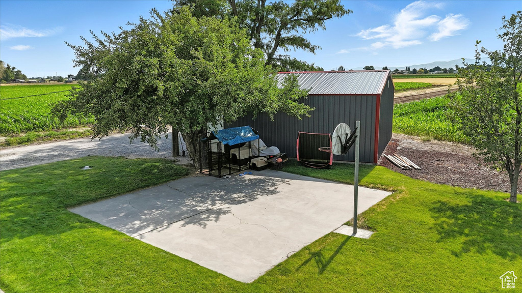 View of patio / terrace featuring a view of countryside, an outbuilding, a mountain view, and agricultural plots