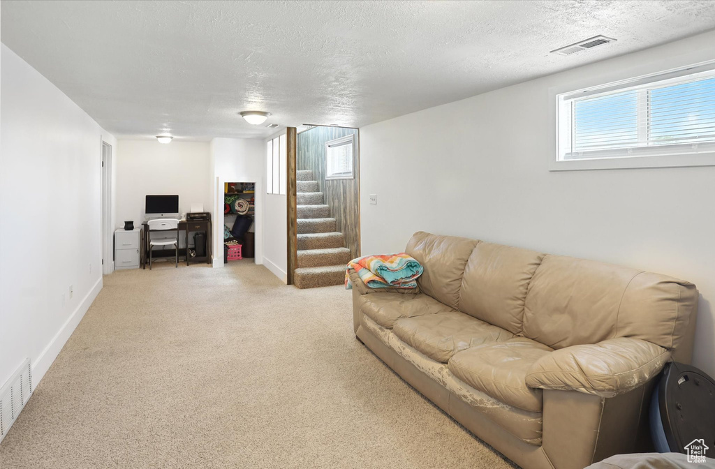 Living area featuring stairway, an office area, light carpet, and a textured ceiling