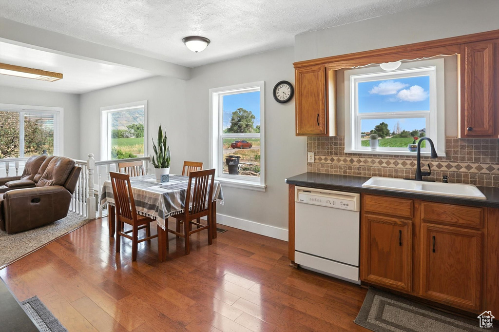 Kitchen with dishwasher, decorative backsplash, dark countertops, brown cabinetry, and a textured ceiling