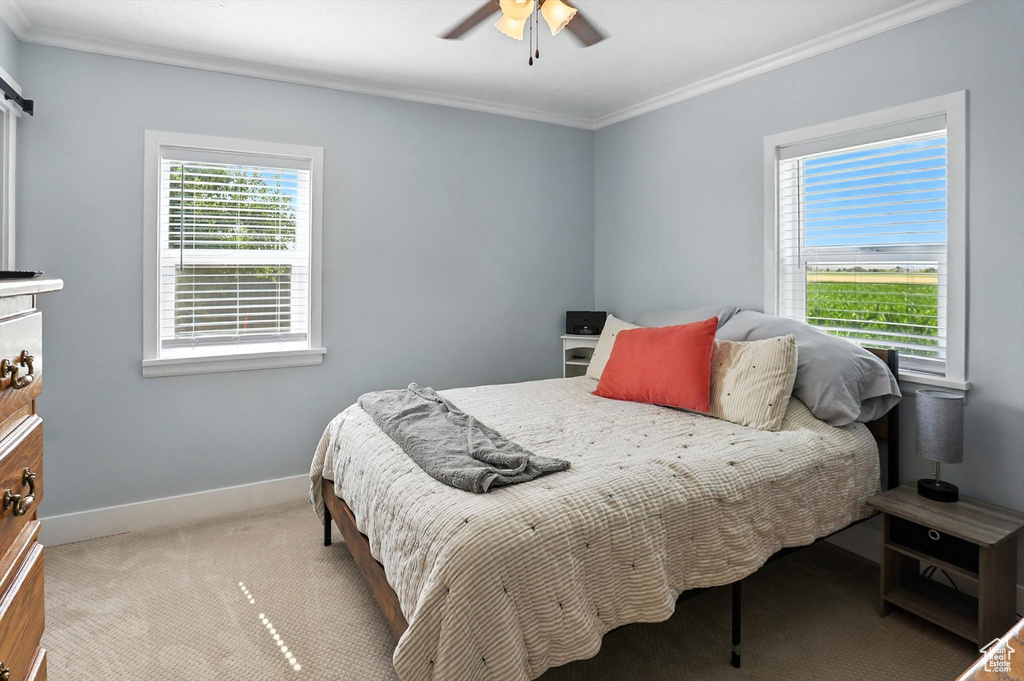 Bedroom with crown molding, light colored carpet, and ceiling fan